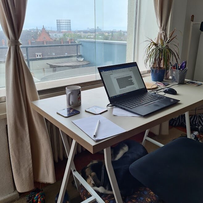 Kris’s desk overlooking Berlin, with a laptop and writing notes